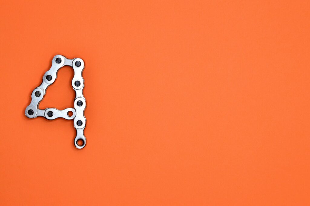 A creative design of the number four formed with a metal chain against an orange background, offering ample copy space.